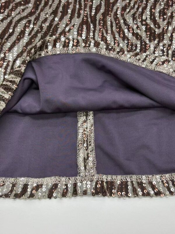 Close-up of a glamorous dress featuring sequins and a purple lining, highlighting intricate details and luxurious fabric for evening wear or special occasions.