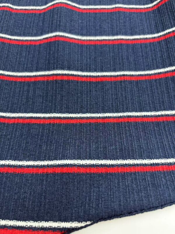 Close-up of navy blue knit fabric with red and white horizontal stripes, showcasing textured material and detailed pattern.