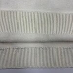 Detailed close-up of white knit fabric showing fine texture and ribbed pattern, ideal for fashion and textile product display.