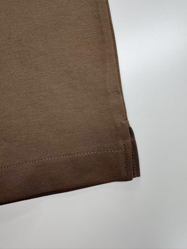 Close-up of brown fabric with stitched hem, showcasing smooth texture and neat finishing.