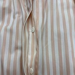 Close-up of a men's pajama shirt with beige and white vertical stripes, featuring a button-down front and a soft, comfortable fabric.