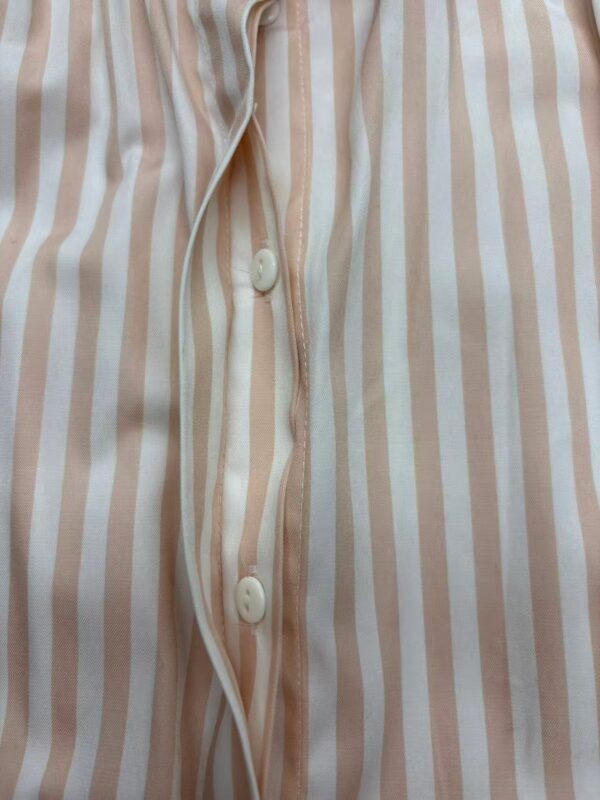 Close-up of a men's pajama shirt with beige and white vertical stripes, featuring a button-down front and a soft, comfortable fabric.