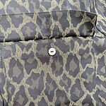 Close-up of a stylish leopard print shirt with a button detail, perfect for fashion-forward outfits and casual wear.