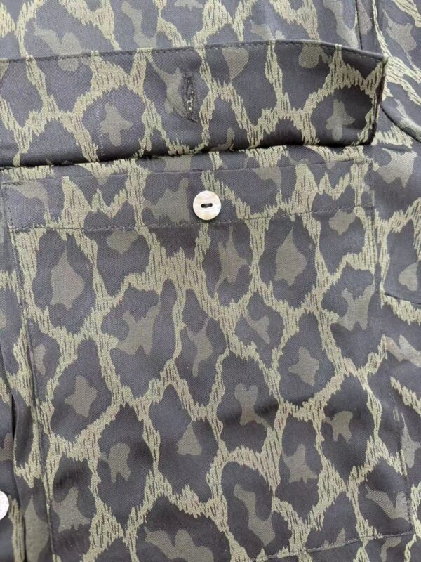 Close-up of a stylish leopard print shirt with a button detail, perfect for fashion-forward outfits and casual wear.