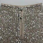 Close-up of a silver sequin dress with a zipper and decorative buttons, perfect for evening wear or special occasions.