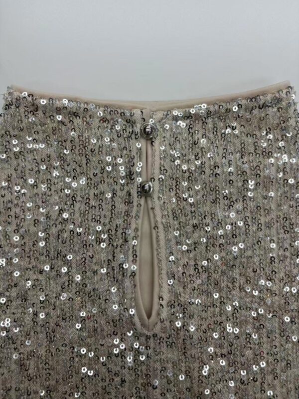 Close-up of a silver sequin dress with a zipper and decorative buttons, perfect for evening wear or special occasions.