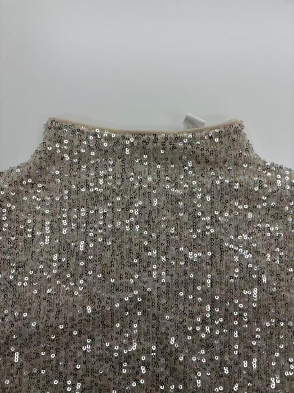 Close-up of a silver sequin dress with a high neckline, perfect for evening events and parties, showcasing sparkling embellishments and luxurious fabric.