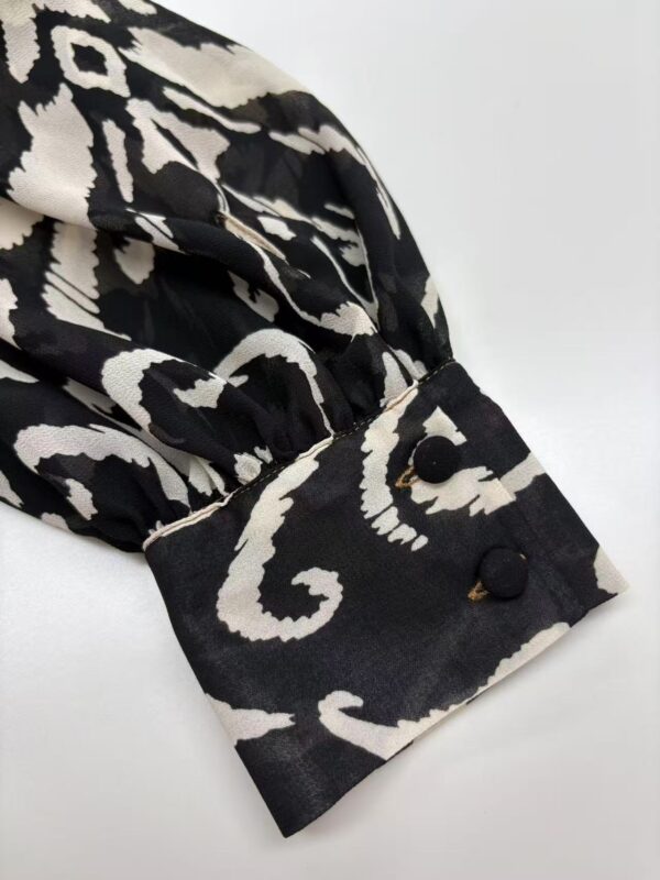 Close-up of a stylish black and white patterned sleeve with buttoned cuff, perfect for fashion-forward outfits.