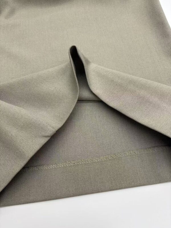 Close-up of khaki fabric with smooth texture and subtle stitching, ideal for stylish clothing and fashion accessories.