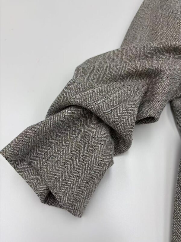 Close-up of a herringbone wool coat sleeve showcasing detailed fabric texture and craftsmanship, perfect for fall and winter fashion.