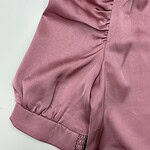 Close-up of a pink satin blouse with ruched sleeve detail and cuff, showcasing luxurious fabric and stylish design for women's fashion.