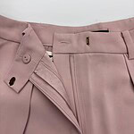 Close-up of pink women's dress pants with zipper and button closure, suitable for formal or office wear.