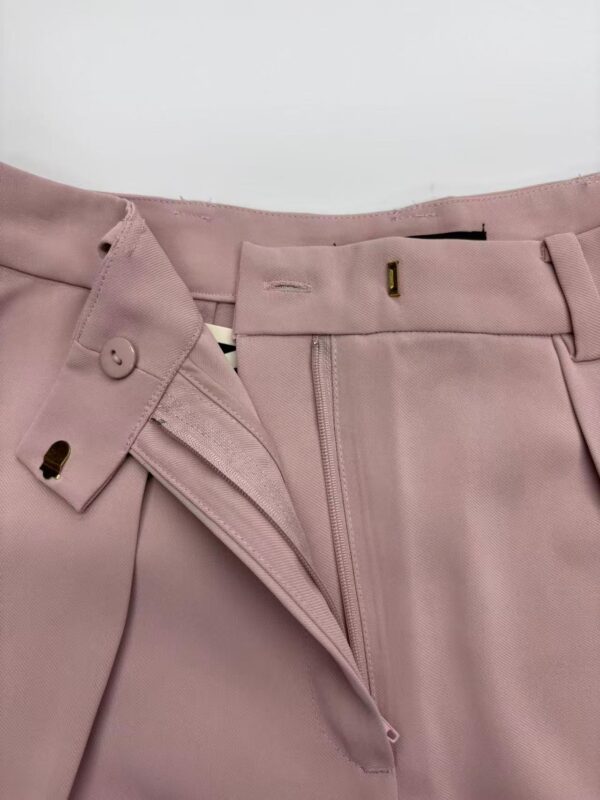 Close-up of pink women's dress pants with zipper and button closure, suitable for formal or office wear.