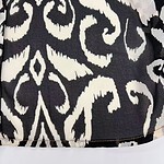Close-up of black fabric with white abstract and geometric pattern, suitable for fashion or home decor.