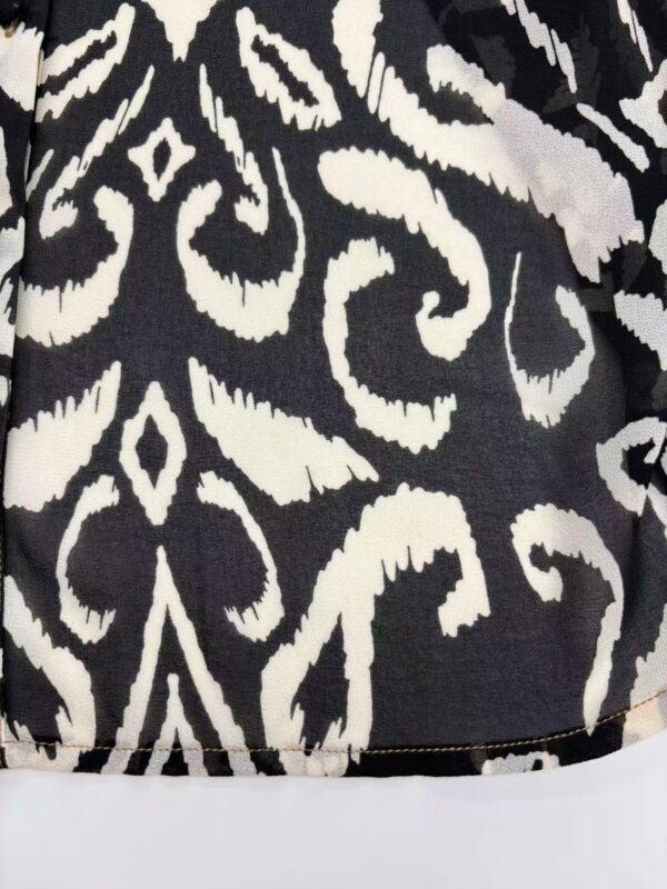 Close-up of black fabric with white abstract and geometric pattern, suitable for fashion or home decor.