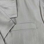 Close-up of light gray suit fabric showing fine texture and tailored stitching, perfect for formal wear and professional attire.