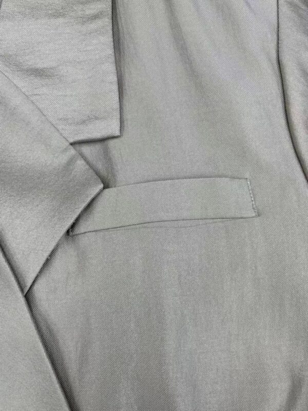 Close-up of light gray suit fabric showing fine texture and tailored stitching, perfect for formal wear and professional attire.