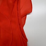 Close-up of a vibrant red dress made from sheer fabric, showcasing stylish design details and craftsmanship.