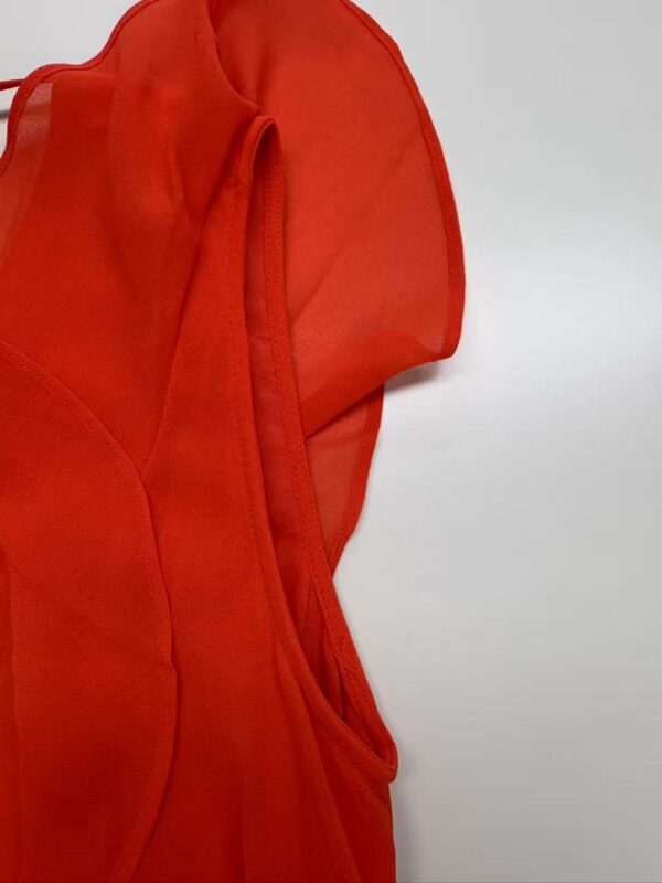 Close-up of a vibrant red dress made from sheer fabric, showcasing stylish design details and craftsmanship.