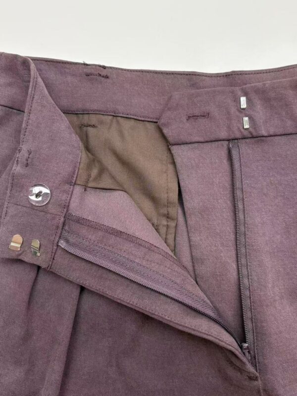 Close-up of stylish mauve women's trousers with zipper and button closure, showcasing high-quality fabric and tailored fit, perfect for casual or formal wear.