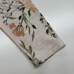Close-up of a fabric sleeve with a delicate floral pattern featuring peach, green, and black accents on a light background.