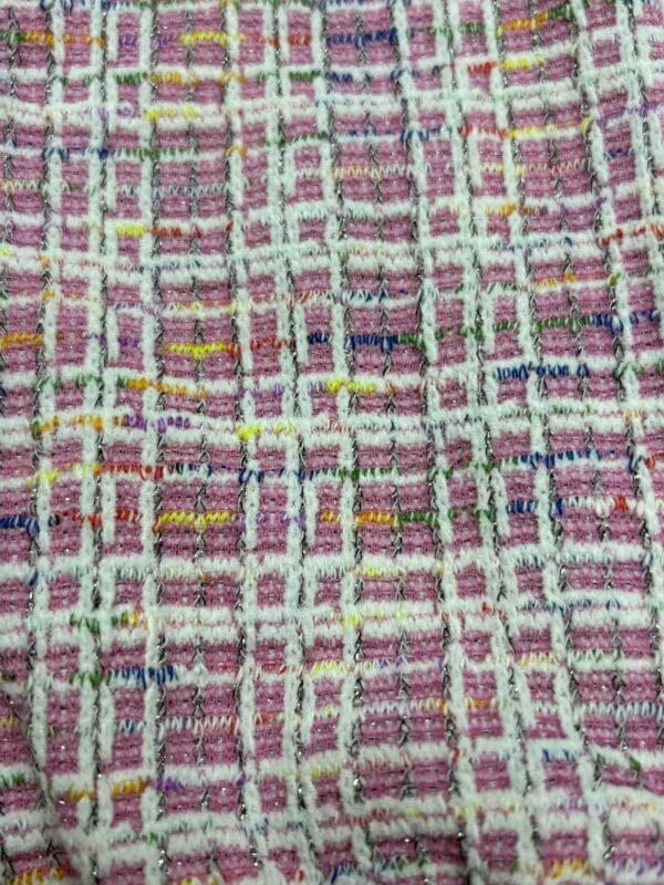 Close-up of vibrant pink, yellow, blue, and white tweed fabric with a textured woven pattern, ideal for fashion and clothing accessories.