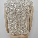 Close-up of a women's jacket with intricate sequin embellishments and beige sleeves, showcasing luxury fashion details.