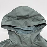 Close-up of a modern green hooded jacket with a high collar, made from waterproof material, perfect for outdoor fashion and weather protection.