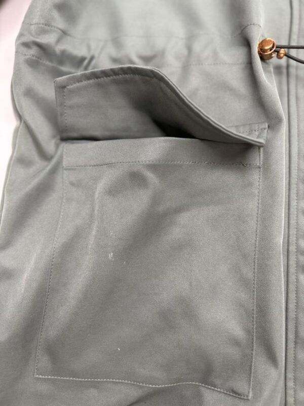 Close-up of gray workwear pants featuring a large front pocket and durable fabric, ideal for professional or casual wear.