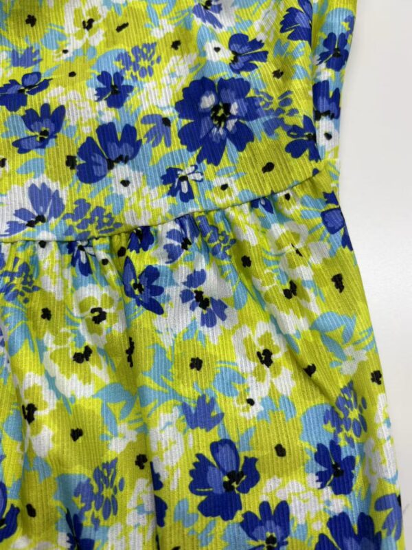 Bright floral summer dress with blue, yellow, and white flowers, featuring a gathered waist and lightweight fabric, perfect for warm weather and casual outings.