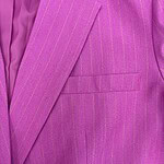 Close-up of a vibrant pink pinstripe suit jacket with a notched lapel and a welt pocket, showcasing high-quality tailoring and fabric detail.