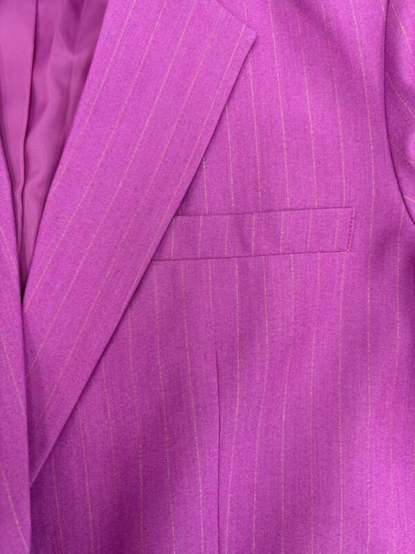 Close-up of a vibrant pink pinstripe suit jacket with a notched lapel and a welt pocket, showcasing high-quality tailoring and fabric detail.