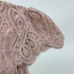 Close-up of a pink lace dress showcasing intricate embroidery and delicate fabric, perfect for fashion and special occasions.