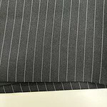 Close-up of dark gray pinstripe fabric with white vertical lines, suitable for business suits or formal wear.