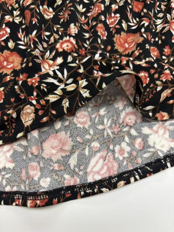 Close-up of floral patterned fabric with black background and colorful flowers, suitable for clothing or accessories.