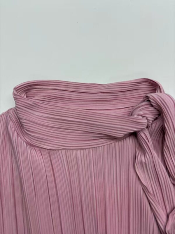 Close-up of a pink pleated skirt with a tied waist, showcasing stylish and feminine fashion suitable for various occasions.