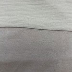 Close-up image showing the detailed texture of light gray fabric, highlighting the smooth and soft material used in fashion clothing.