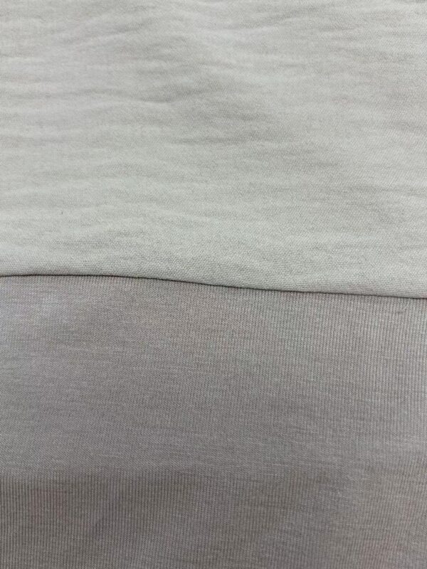 Close-up image showing the detailed texture of light gray fabric, highlighting the smooth and soft material used in fashion clothing.