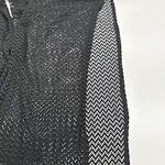 Close-up of a black mesh dress showcasing intricate see-through fabric and detailed pattern, perfect for stylish evening wear or fashion-forward occasions.