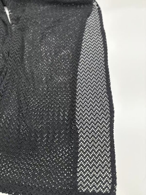 Close-up of a black mesh dress showcasing intricate see-through fabric and detailed pattern, perfect for stylish evening wear or fashion-forward occasions.