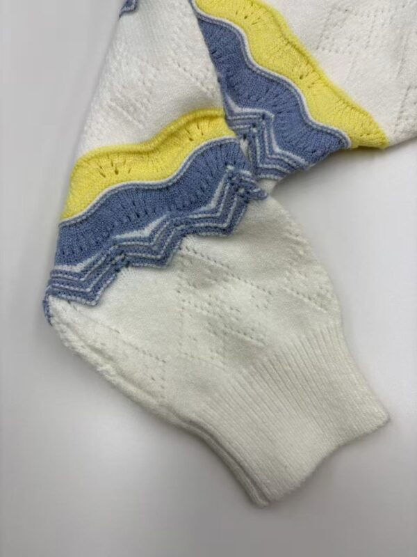 Close-up of a knitted sock featuring a zigzag pattern in blue, yellow, and white colors, showcasing detailed stitching and vibrant design.