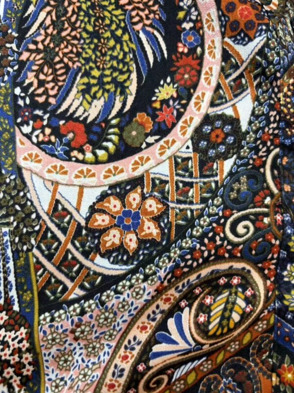 Close-up of intricate embroidered textile featuring floral and geometric patterns in vibrant colors.