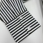 Close-up of a black and white striped shirt cuff with two shiny buttons, showcasing stylish fashion details.