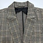 Close-up of women's houndstooth wool coat with classic collar and tailored fit, perfect for fall and winter fashion.