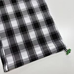 Close-up of black and white checkered fabric with a green drawstring at the corner, ideal for fashion or home decor.