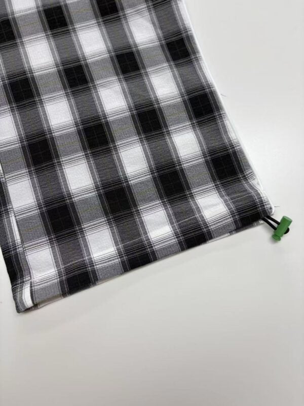 Close-up of black and white checkered fabric with a green drawstring at the corner, ideal for fashion or home decor.