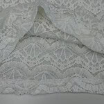 Close-up of delicate white lace fabric with intricate patterns, ideal for fashion and bridal wear.