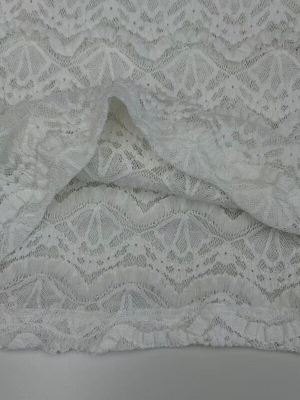 Close-up of delicate white lace fabric with intricate patterns, ideal for fashion and bridal wear.
