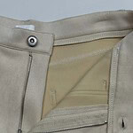 Close-up of beige fashion trousers showing zipper and button closure, with a smooth fabric finish and tailored design, ideal for stylish casual or formal wear.