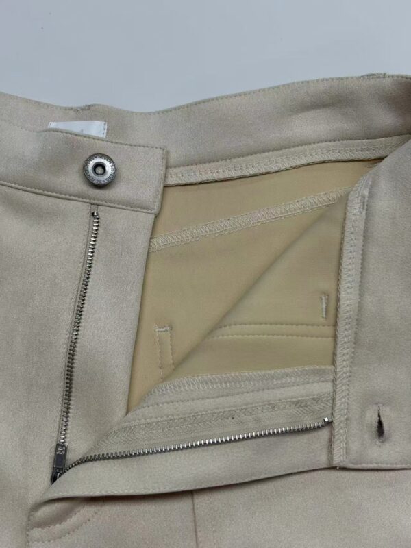 Close-up of beige fashion trousers showing zipper and button closure, with a smooth fabric finish and tailored design, ideal for stylish casual or formal wear.